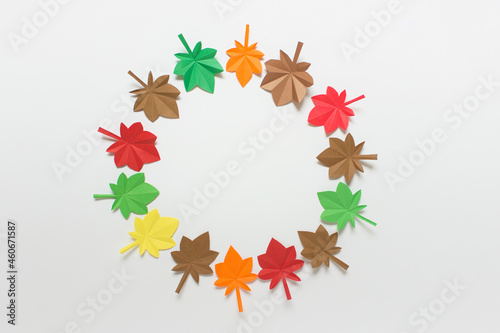 Simple background with autumn colorful maple origami folded paper leaves arranged in circle on white background