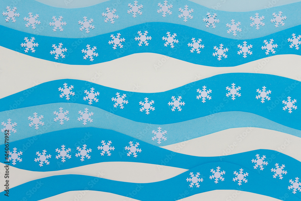 Christmas background with white blue wavy paper sheets and white decorative snowflakes