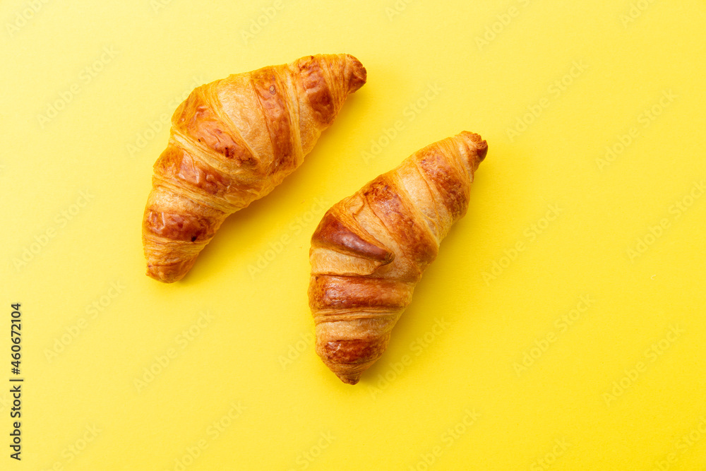 Two croissants on a yellow background.