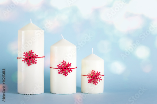 Chrsitmas, New Year composition with three white candles, red wooden snowflkes on blue background photo