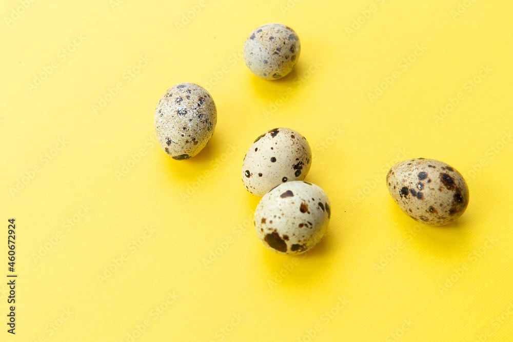 Several quail eggs on a yellow background.