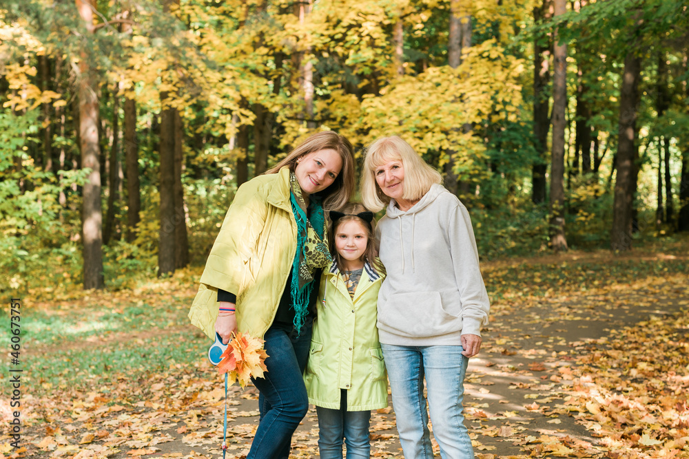 Portrait of three generations of happy beautiful woman looking at camera, hugging and smiling in autumn nature
