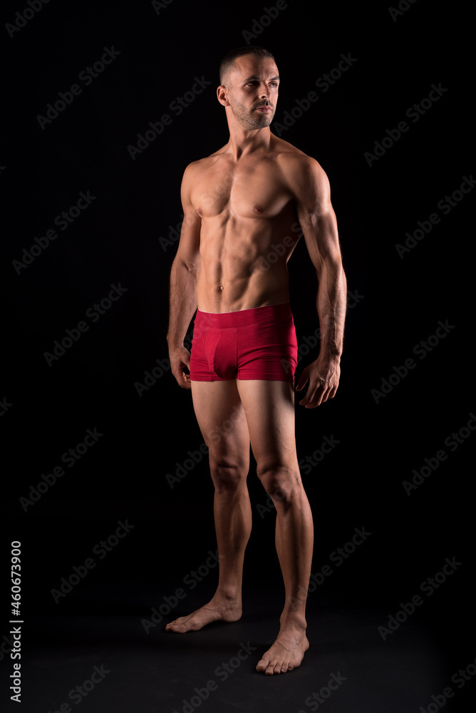 Studio photo of strong male in pants standing, black background Studio photo of strong male in pants standing, black background