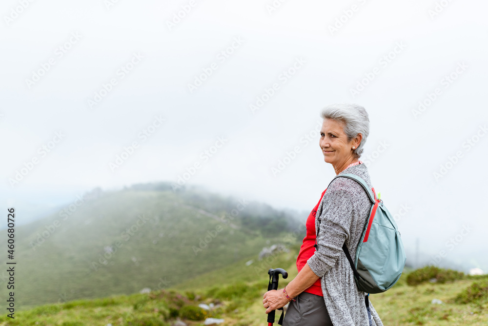 older woman with gray hair hiking on a cloudy day.