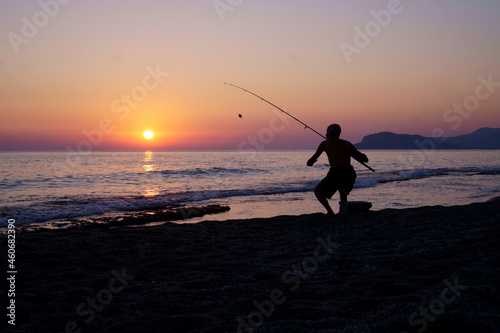 A fisherman at sunset fishing on the sea