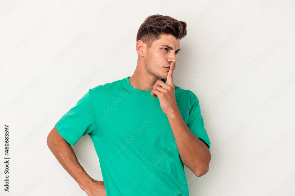 Young caucasian man isolated on white background keeping a secret or asking for silence.