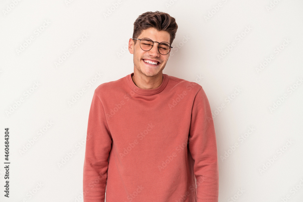 Young caucasian man isolated on white background laughs and closes eyes, feels relaxed and happy.