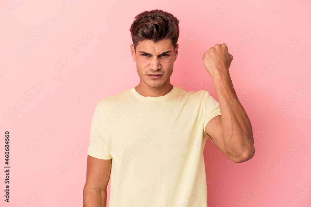 Young caucasian man isolated on pink background showing fist to camera, aggressive facial expression. Young caucasian man isolated on pink background showing fist to camera, aggressive facial expression.