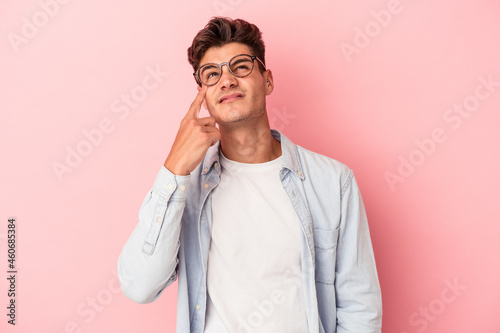 Young caucasian man isolated on pink background crying, unhappy with something, agony and confusion concept.