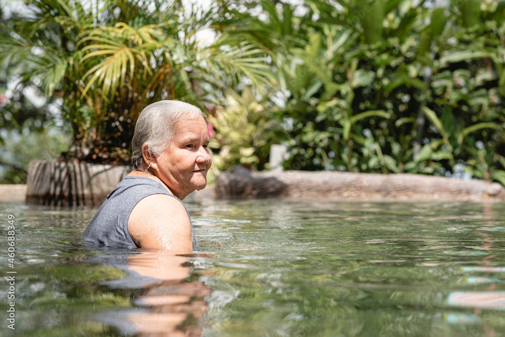 Fototapeta premium hermosa anciana disfrutando del agua en una piscina natural de aguas termales