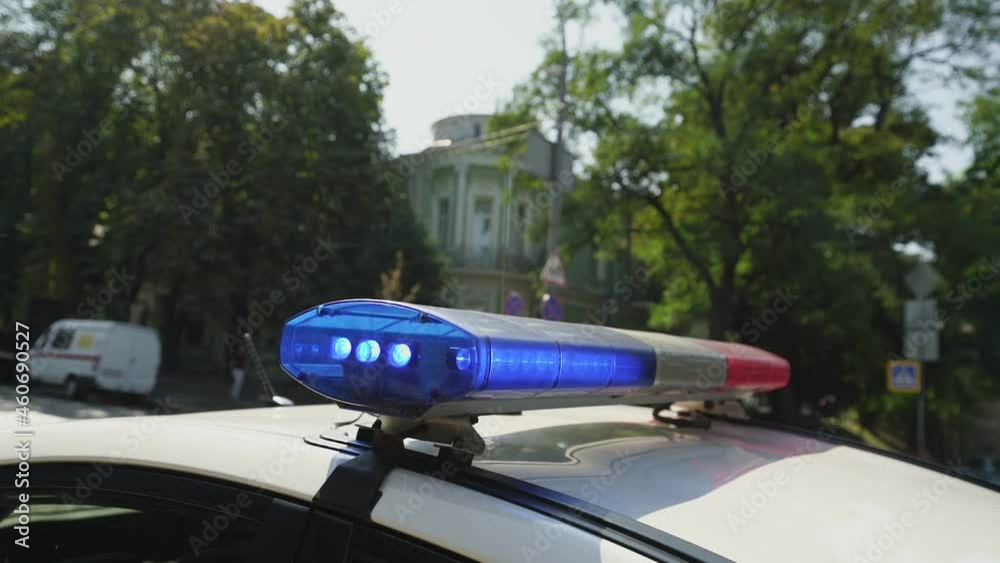 Police car with flashing red and blue siren on roof at city street