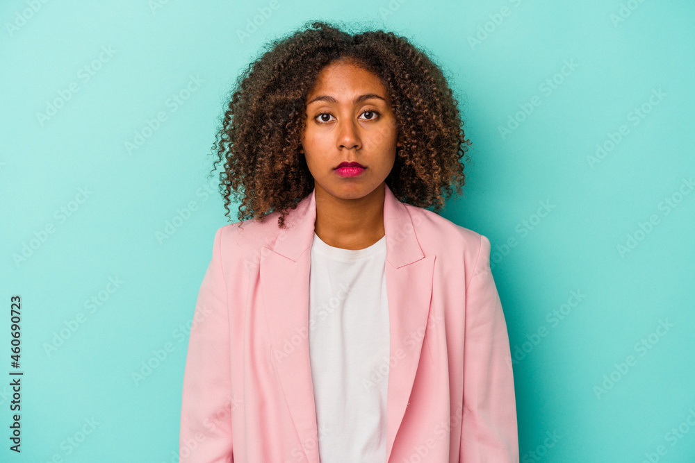 Fototapeta premium Young african american woman with curly hair isolated on blue background sad, serious face, feeling miserable and displeased.