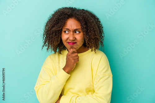 Young african american woman with curly hair isolated on blue background suffers pain in throat due a virus or infection.