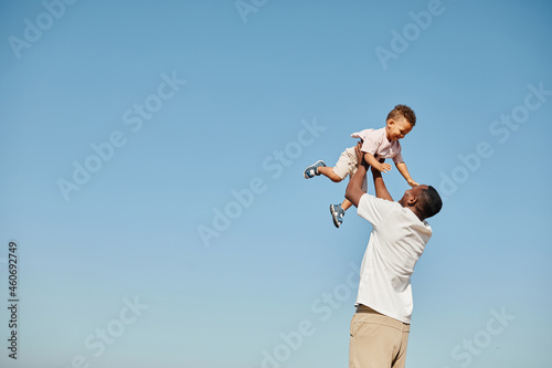 Canvastavla Minimal portrait of happy African-American father playing with cute baby and thr