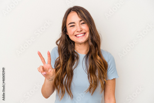 Young caucasian woman isolated on white background showing victory sign and smiling broadly.