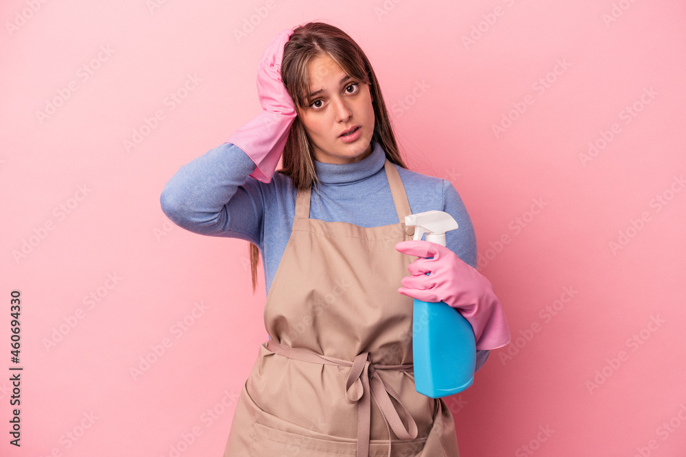 Young caucasian cleaner woman holding spray isolated on pink background being shocked, she has remembered important meeting. Young caucasian cleaner woman holding spray isolated on pink background being shocked, she has remembered important meeting.