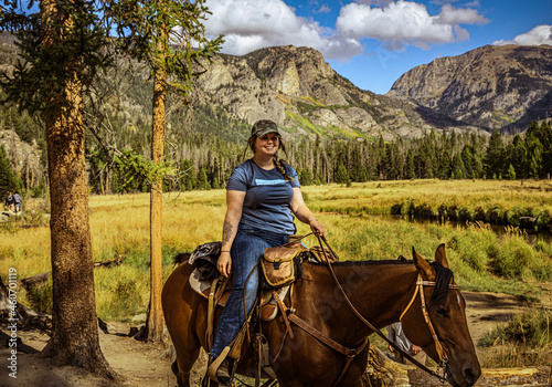 Картината върху платно Young attractive woman smiling at cameras while riding her horse in Rocky Mounta