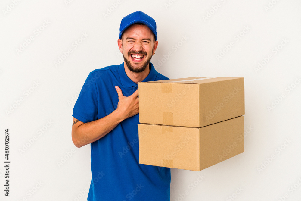 Young caucasian delivery man with tattoos isolated on white background laughs out loudly keeping hand on chest. Young caucasian delivery man with tattoos isolated on white background laughs out loudly keeping hand on chest.