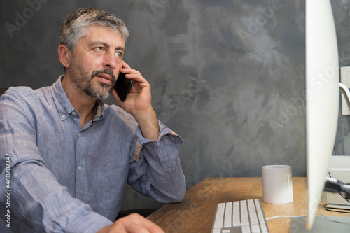 Fotografie Un homme d'âge mûr 50 ans est en train de travailler au bureau, il téléphone dev