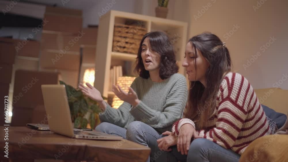 A female couple makes a video call to their new home during the move. Happy friends sharing their joy with family making a call with a laptop. A female couple makes a video call to their new home during the move. Happy friends sharing their joy with family making a call with a laptop.