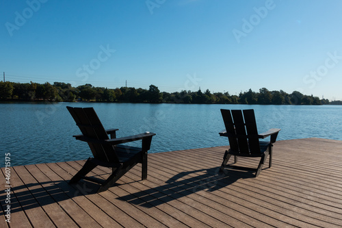 Two Lounge Chairs on Lakeside Dock with Shadows in the Morning Sunlight 