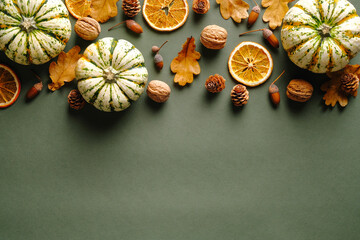 Happy Thanksgiving day concept. Autumn composition with ripe pumpkins, fallen leaves, dry oranges, acorns, nuts on rustic green table. Flat lay, top view, copy space.