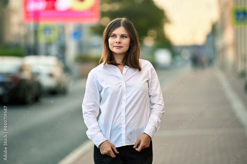 White young woman in shirt stands near traffic at summer day. White young woman in shirt stands near traffic at summer day.