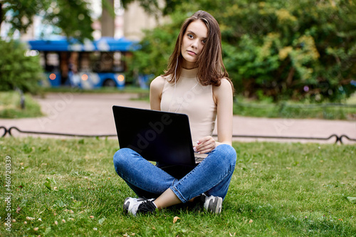 Online learning in park by slim young woman with laptop.