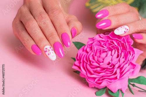 Close up view of beautiful female hands with romantic manicure nails  pink gel polish  peonies flowers design 