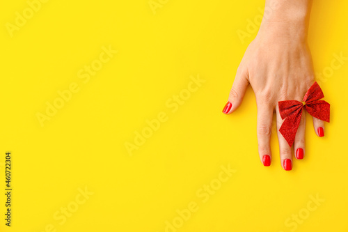 Female hand with beautiful manicure on yellow background, closeup