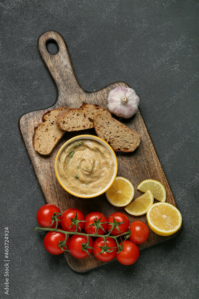 Bowl with tasty baba ghanoush, bread, lemon and tomato on black background Bowl with tasty baba ghanoush, bread, lemon and tomato on black background