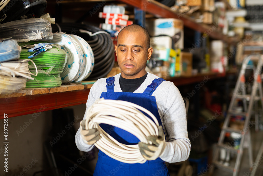 Fototapeta premium Confident latin american handyman man choosing materials for overhauls in building materials store