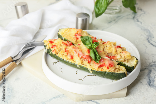 Plate with quinoa stuffed zucchini boats on light background
