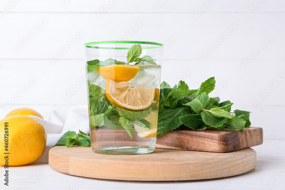 Fototapeta premium Glass of tasty mint tea with lemon on white wooden background