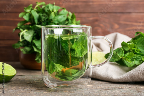 Glass cup of tasty mint tea on wooden background