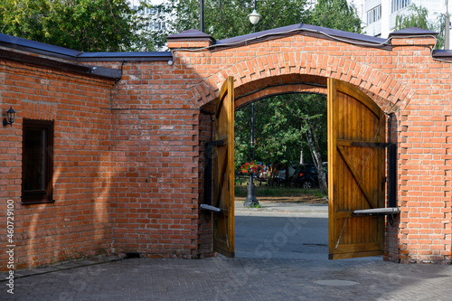 Bild auf Leinwand Wooden half-open gate in a brick fence in the courtyard of the 19th century merc