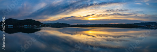Sunrise and cloud reflections panorama waterscape at Woy Woy on the Central Coast of NSW, Australia.