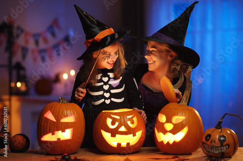 Happy family mother and little girl daughter in witch costumes celebrating Halloween at home photo