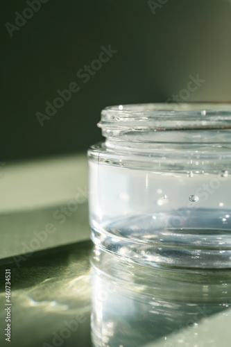 Transparent gel in a jar on a green background.