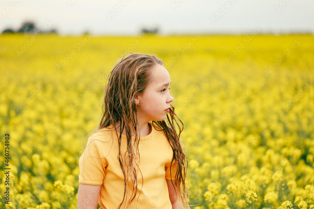 Pretty long haired girl playing in vibrant canola field in full bloom Pretty long haired girl playing in vibrant canola field in full bloom
