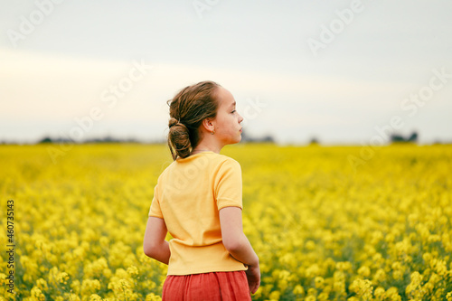 Pretty long haired girl playing in vibrant canola field in full bloom