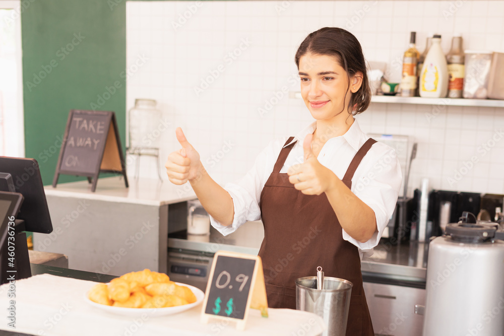 Beautiful caucasian barista woman give thumbs up at the coffee bar in cafe coffee shop Beautiful caucasian barista woman give thumbs up at the coffee bar in cafe coffee shop