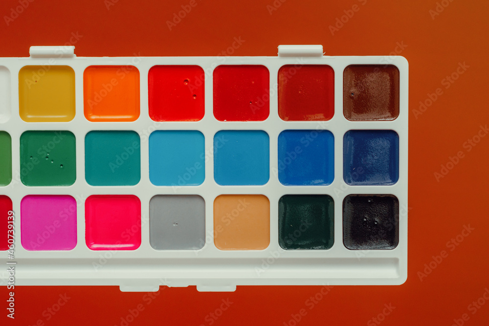 watercolor paints in a palette on an orange background