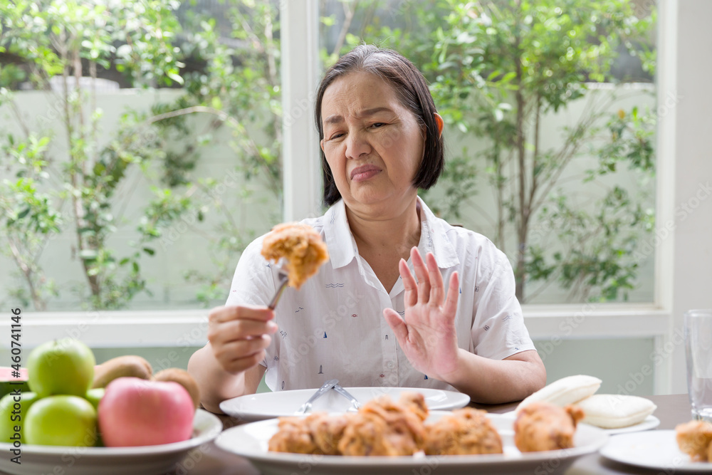 Senior Asian woman don't like fried chicken. Elderly Asian woman don’t eat junk food or fast food. Health care and ageing concept