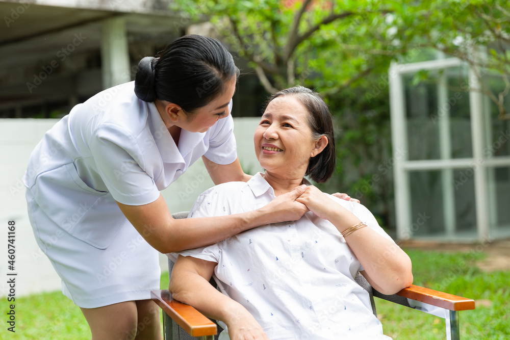Fototapeta premium Caring asian medical nurse comforting senior patient in outdoor and smiling patient is holding caregiver for a hand.