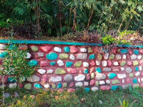 Colorful stones in the wall of around a park at morning in sunlight. Colorful wall stones of a park.