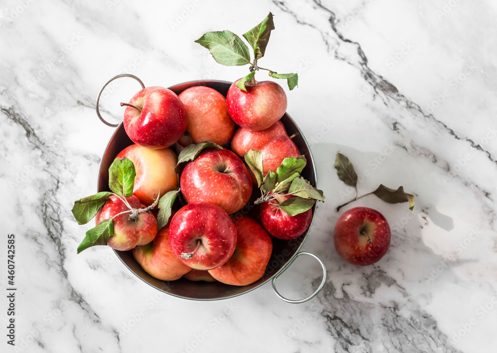 Autumn red ripe apples in a metal basket on a marble background, top view Autumn red ripe apples in a metal basket on a marble background, top view