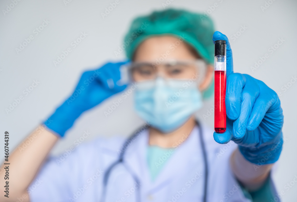 Healthcare worker holding a blood test tube in her hand. A test tube is a glass container used in a scientific laboratory.