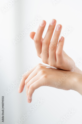 Hand moisturizing. Skin care. Hydrating treatment. Closeup of woman palms applying organic smoothing cream product on light background.