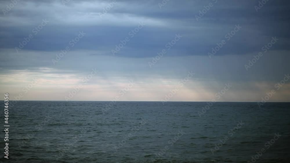 Thunderclouds hang over the stormy sea. It's raining heavily on the horizon. Thunderclouds hang over the stormy sea. It's raining heavily on the horizon.